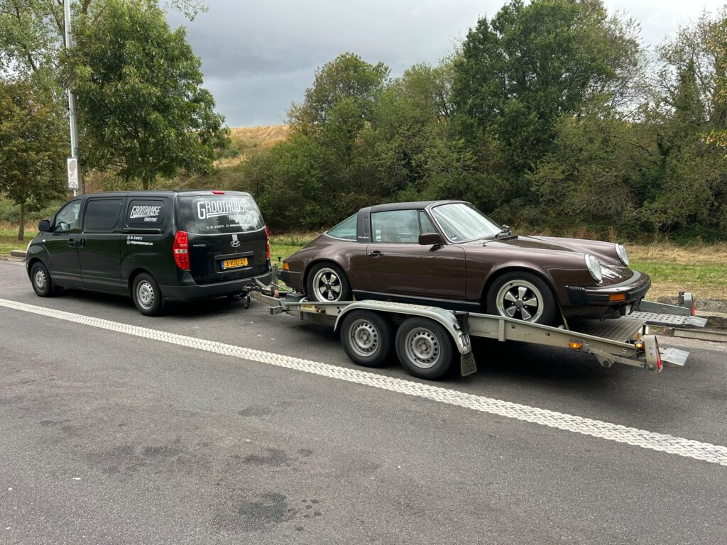 Klassieke auto op de aanhanger achter onze bus